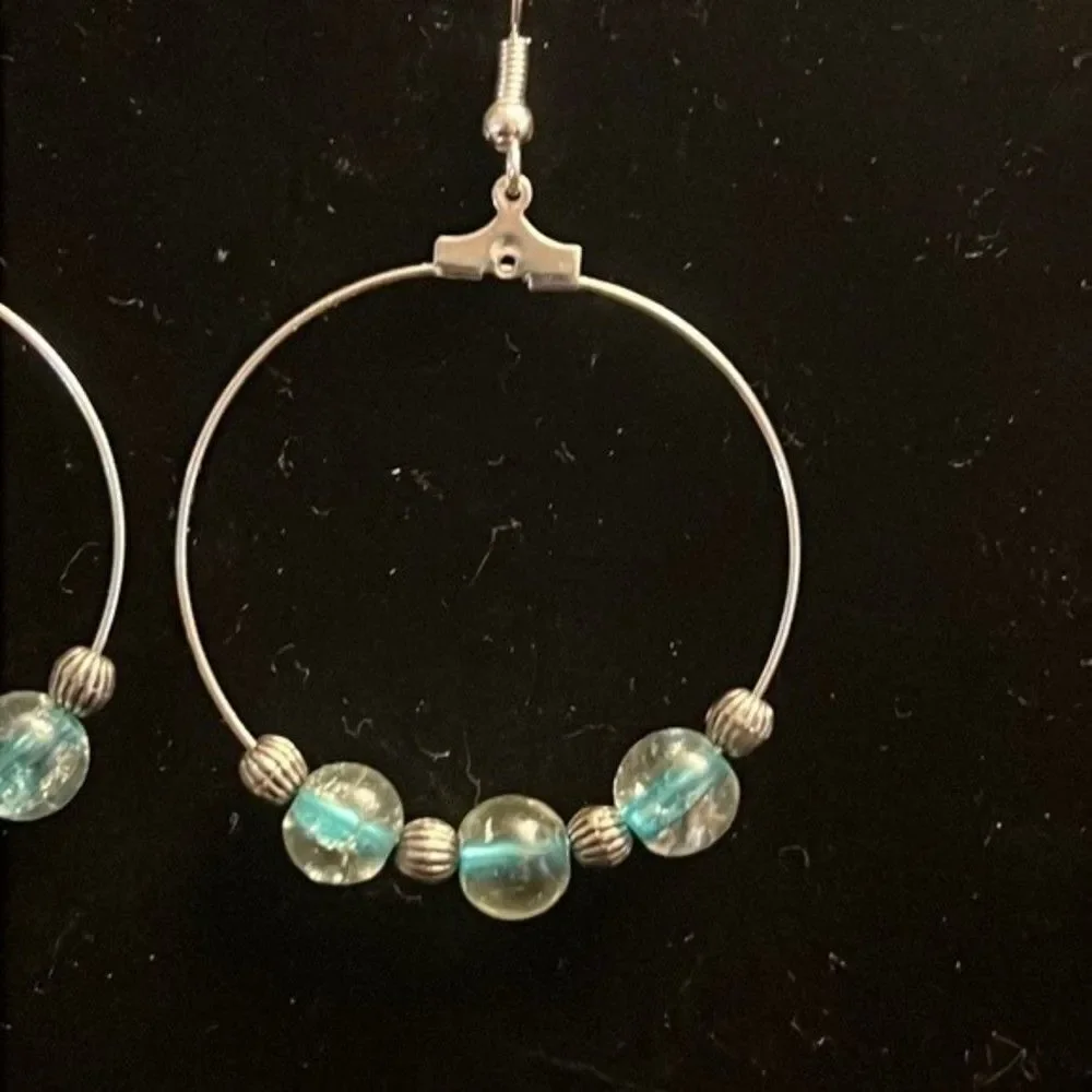 Handcrafted silver tone hoop earrings with clear and blue beading.